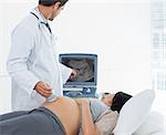 Male doctor performing ultrasound on pregnant woman in clinic