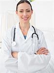 Portrait of confident female doctor smiling while standing arms crossed in clinic