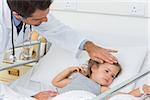 Male doctor checking temperature of sick girl in hospital ward