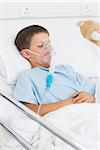 Sick little boy with oxygen mask in hospital ward