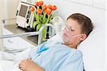 Sick little boy wearing oxygen mask in hospital ward