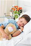 Sick little boy with teddy bear sleeping in hospital bed
