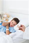 Doctor holding asthma inhaler with sick boy in hospital bed