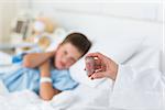 Doctor holding pill bottle with sick boy in hospital bed