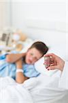 Closeup of doctor holding pill bottle with sick boy in ward