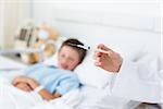 Closeup of doctor holding syringe with sick boy in hospital bed