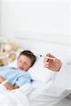 Closeup of doctor holding syringe with sick boy in hospital