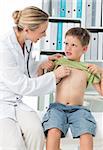 Female pediatrician examining boy with stethoscope in clinic