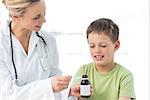 Female pediatrician giving little boy syrup in hospital