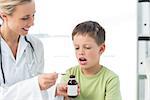 Female doctor giving little boy cough syrup in hospital