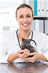 Portrait of happy female vet holding kitten in clinic