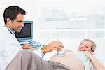 Smiling pregnant blonde woman having an ultrasound scan at the hospital