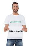Smiling young male volunteer holding 'thank you' paper over white background