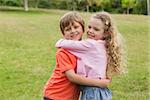 Portrait of two smiling kids hugging at the park