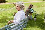 Happy woman sitting on bench while man watering young plant at the park