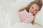 Portrait of a smiling young girl resting in bed at home