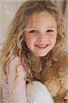 Close-up portrait of a young smiling girl with blond hair