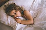 High angle portrait of a young girl resting in bed at home