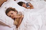 Portrait of a young girl and boy sleeping in bed at home