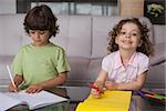 Portrait of siblings drawing in the living room at home