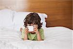 Portrait of a young boy with digital camera in bed at home