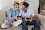 Cheerful couple playing video games in the living room at home