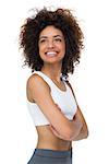 Smiling fit young woman standing with arms crossed over white background