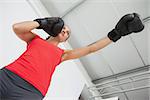 Low angle view of a determined female boxer focused on her training at gym