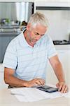 Focused man figuring out his finances at home in the kitchen