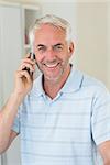 Smiling man on a phone call looking at camera at home in the kitchen
