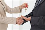 Estate agent giving house key to customer in empty house