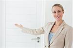 Smiling estate agent showing door to camera in empty house