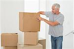 Smiling man looking at cardboard moving boxes in new home