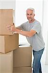 Happy man moving cardboard moving boxes in new home