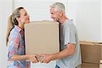 Happy couple carrying cardboard moving boxes  in new home