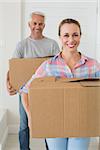 Happy couple carrying cardboard moving boxes in new home