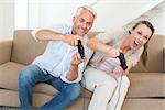 Happy couple having fun on the couch playing video games at home in the living room