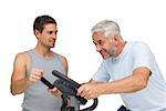 Determined mature man on stationary bike with trainer over white background