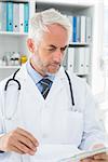 Concentrated male doctor looking at reports in the medical office