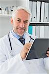 Portrait of a confident smiling male doctor using digital tablet at medical office