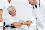 Side view of a smiling senior patient and doctor shaking hands in the medical office