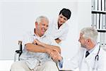 Happy senior patient and doctor shaking hands in the medical office