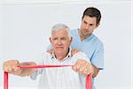 Male physiotherapist massaging senior mans back in the medical office