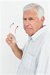 Portrait of a senior man holding glasses over white background