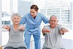 Portrait of a female therapist assisting senior couple with exercises in the medical office