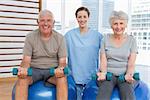 Female therapist assisting senior couple with dumbbells in the medical office