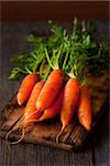 Bunch of fresh carrots  on an old wooden cooking board.