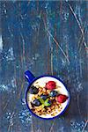 Yogurt witn granola and fresh berries on an old wooden board.