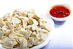 Chinese Food:  boiled dumplings with sauce on a white background