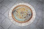 Budapest rusted sewer cap surrounded by pavement granite stones